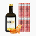 En GINSTR Pink Grapefruit Ginpakke fra Stuttgart Distillery med en flaske gin, fire Fever-Tree Sparkling Pink Grapefruit-dåser og tørrede appelsinskiver arrangeret mod en hvid baggrund.
