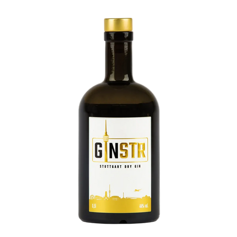 En mørk glasflaske med GINSTR Stuttgart Dry Gin fra Stuttgart Distillery, 44 % vol., med guldhætte og en hvidgylden etiket med mærkenavnet og byens skyline - en ideel gin til Gin & Tonic, der indfanger Stuttgarts ånd.