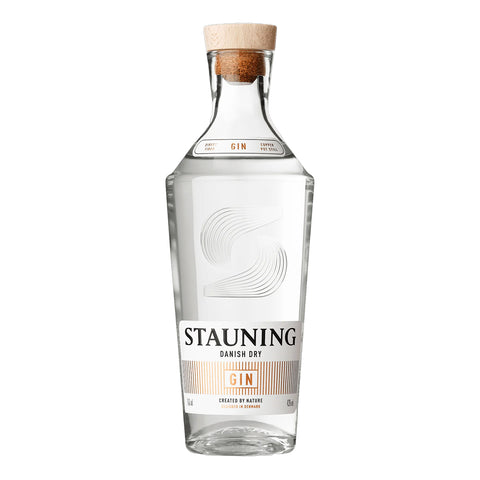 En klar glasflaske med Stauning Danish Dry Gin fra Stauning Whisky, med træprop, en moderne etiket i hvid og guld og et præget frontdesign.
