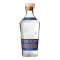 En flaske Stauning Navy Strength Gin fra Stauning Whisky, med korkprop og en blå og guldfarvet etiket, står oprejst på en hvid baggrund.