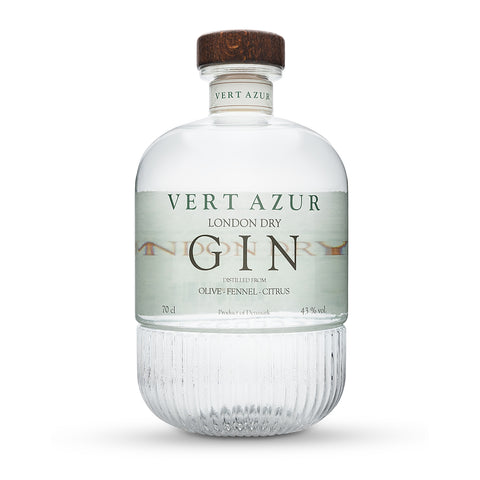 En klar 70 cl flaske Vert Azur Gin fra Vert Azur med en træhætte, ribbet nedre halvdel og en etiket med teksten "Olive - Fennel - Citrus". Ginen har en alkoholprocent på 43,8.